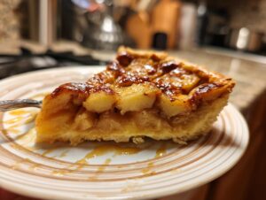 A close-up of a slice of apple pie dump cake on a plate, showing tender baked apples and a golden crust.