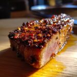 A perfectly cooked Blackened Tuna Steak with a spicy crust and moist interior, glistening on a wooden board.