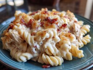 A close-up of a serving of chicken bacon ranch casserole featuring rotini pasta, creamy sauce, shredded chicken, and crispy bacon bits.