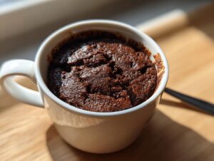 A close-up of a freshly baked Cottage Cheese Microwave Brownie in a white mug, ready to eat.