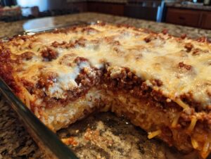 Close-up of a creamy baked spaghetti casserole with layers of spaghetti, ricotta cheese, and meat sauce, topped with melted mozzarella.