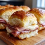 Close-up of a perfectly golden Ham and Cheese Slider, showcasing melted cheese and layers of ham on a soft bun.