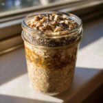 Close-up of high protein overnight oats in a glass jar, topped with chia seeds and granola.