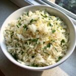 A close-up of fluffy Mediterranean lemon rice mixed with fresh chopped parsley and lemon zest.