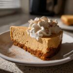 A slice of no bake pumpkin cheesecake topped with whipped cream and cinnamon.