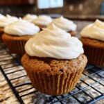 Close-up of a perfectly baked pumpkin spice cupcake topped with fluffy cream cheese frosting.