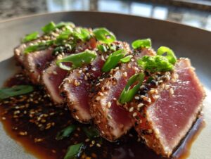 Close-up of perfectly seared ahi tuna slices coated in sesame seeds and served with a savory sauce.