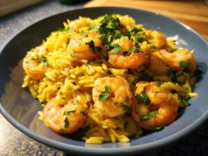 Close-up of a bowl of shrimp orzo in lemon garlic sauce, garnished with fresh parsley.