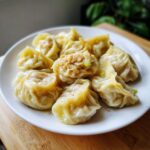 A plate full of steaming Traditional Chinese Dumplings, showcasing their delicate pleats and savory filling.