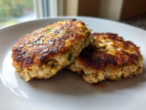 Two perfectly cooked Tuna Patties, golden brown and slightly crispy, served on a white plate.