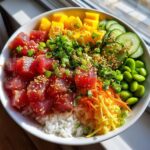 A vibrant Tuna Poke Bowl filled with fresh tuna cubes, diced mango, cucumber slices, edamame, and shredded carrots on a bed of rice.