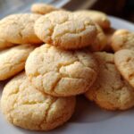 A close-up of a pile of golden 3 ingredient butter cookies, lightly coated in sugar.