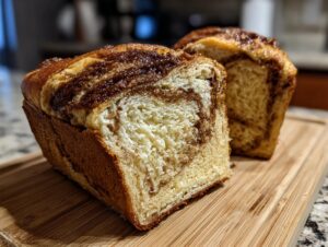 Close-up of a freshly baked Amish cinnamon bread loaf, sliced to reveal its swirled cinnamon filling and soft texture.