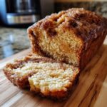 A close-up of a sliced loaf of Amish cinnamon bread with a glistening glaze and visible cinnamon swirls.