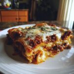 A hearty slice of beef lasagna with layers of pasta, rich meat sauce, and melted cheese, topped with herbs.