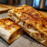 Close-up of cheesy chicken garlic wraps, cut in half to reveal shredded chicken and melted cheese inside.
