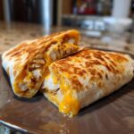 Close-up of cheesy garlic chicken wraps cut in half, showing melted cheese and shredded chicken inside.