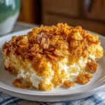 A close-up of a serving of chicken hashbrown casserole topped with crispy, golden cornflakes.