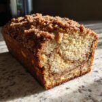 A close-up of a delicious Cinnamon Crunch Banana Bread loaf with a crumbly topping.