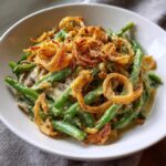 A bowl of creamy copycat French's green bean casserole topped with crispy fried onions.