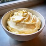 A bowl filled with fluffy, smooth cream cheese frosting, ready to be used for baking.