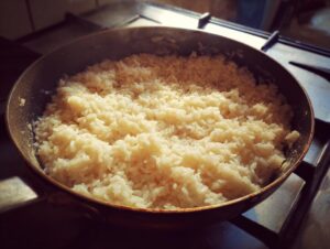 Close-up of creamy risotto being cooked in a pan on a stovetop.