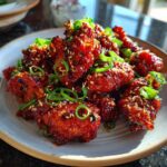 Close-up of crispy, glazed Dragon Chicken pieces topped with sesame seeds and chopped green onions.