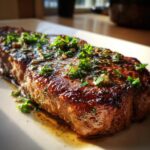 Close-up of a perfectly cooked garlic butter steak, glistening with sauce and topped with fresh parsley.