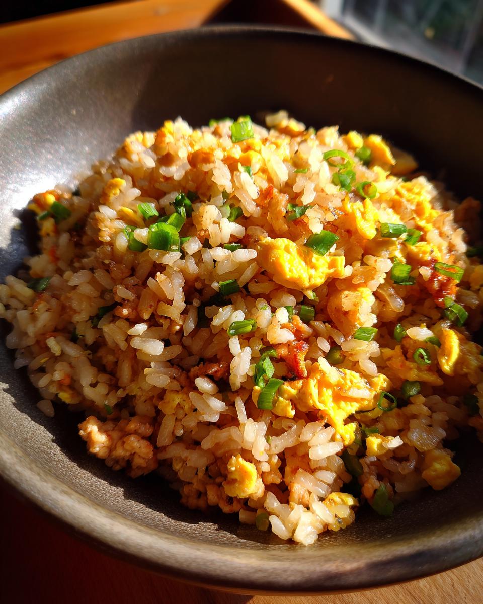 A close-up of delicious ground chicken fried rice, featuring fluffy rice, scrambled eggs, and green onions.