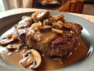A close-up of a juicy hamburger steak smothered in rich mushroom gravy.