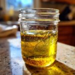 A mason jar filled with homemade vinaigrette salad dressing, showing layers of oil, vinegar, and spices.