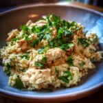A close-up of a creamy Instant Pot chicken and rice dish topped with fresh parsley.