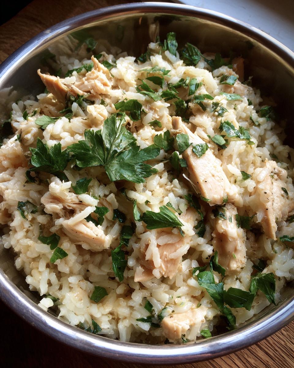 A close-up of a bowl of Instant Pot chicken and rice, generously garnished with fresh parsley.