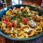 A close-up of Italian drunken noodles with creamy sauce, meatballs, red peppers, and parsley.