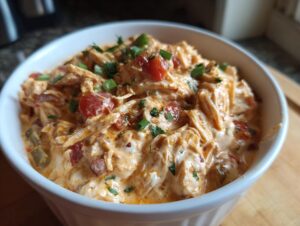 A close-up of creamy Keto Cream Cheese Chicken Chili in a white bowl, garnished with chopped green onions and parsley.