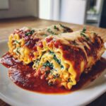 Close-up of two delicious lasagna roll ups, filled with spinach and cheese, topped with marinara sauce and melted mozzarella.