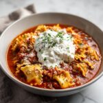 A comforting bowl of lasagna soup with ricotta cheese and fresh parsley, featuring lasagna noodles in a rich tomato sauce.