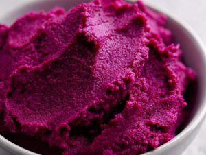 Close-up of creamy, vibrant mashed purple sweet potatoes in a white bowl.