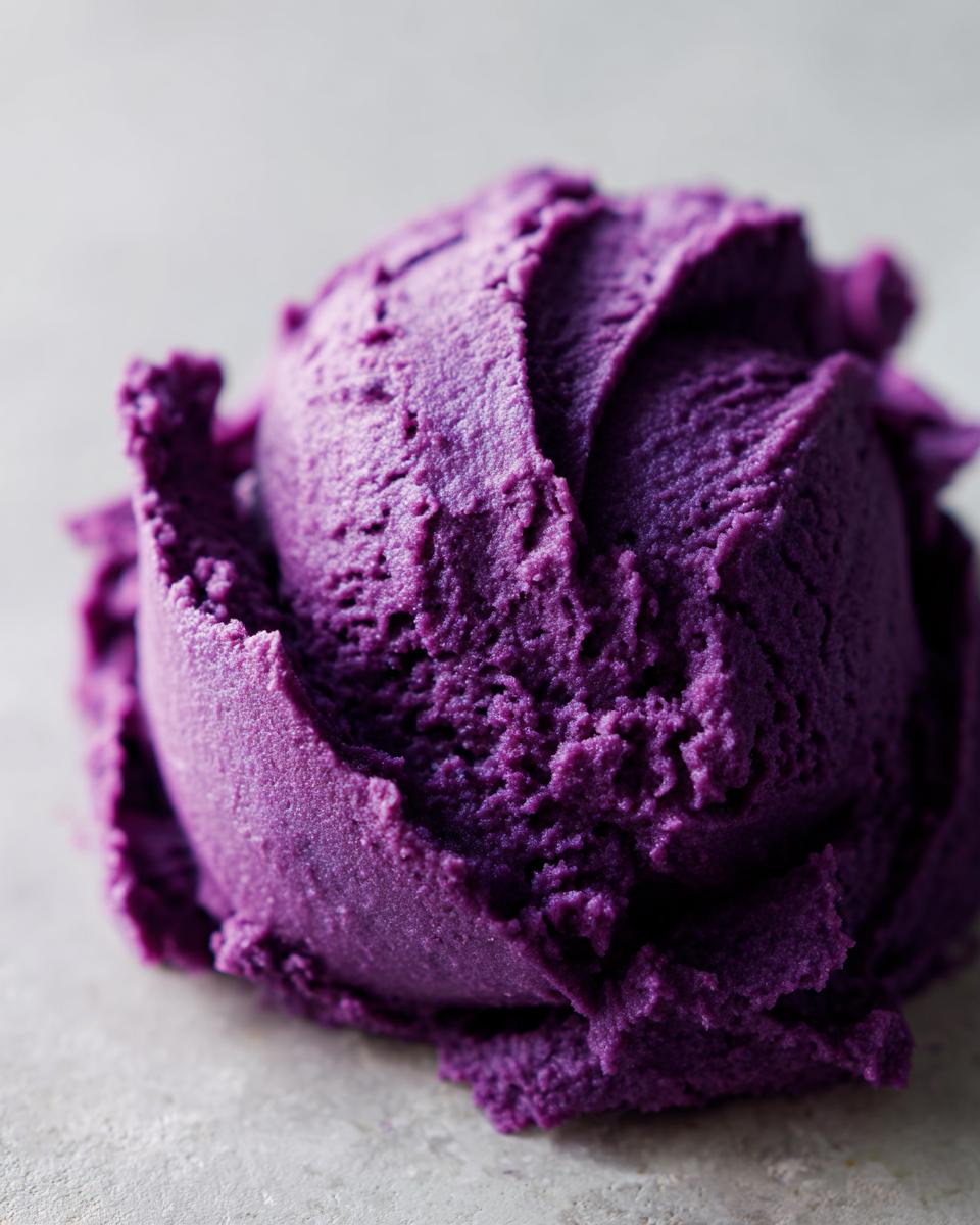 A close-up of a perfectly scooped mound of vibrant purple mashed sweet potatoes.