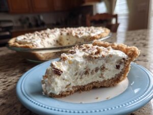 A slice of delicious no-bake Pecan Cream Pie on a blue plate, topped with chopped pecans.