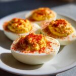 Close-up of four perfect deviled eggs, generously topped with creamy filling and sprinkled with paprika.