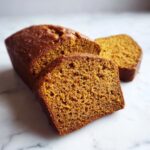 Close-up of moist pumpkin banana bread, with two slices cut from the loaf, showing a tender crumb.
