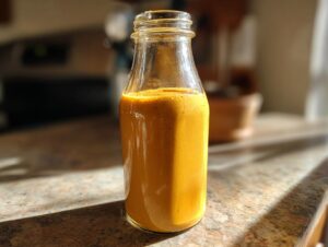 A glass bottle filled with homemade pumpkin spice coffee creamer, bathed in sunlight.