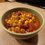 A close-up of a bowl filled with delicious ranch taco soup, featuring ground beef, kidney beans, corn, and tomatoes.