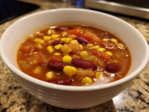 A close-up of a white bowl filled with delicious ranch taco soup, featuring kidney beans, corn, and diced tomatoes.