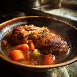 A steaming bowl of slow cooker chicken stew with tender chicken, carrots, and celery in a rich broth.