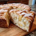 A slice of delicious sourdough apple fritter focaccia, drizzled with white glaze, on a wooden board.