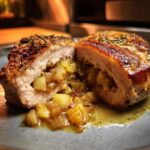 A close-up of juicy apple and rosemary stuffed pork chops, cut in half to reveal the delicious filling.