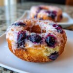 Close-up of a delicious Blueberry Buttermilk Donut with a shiny glaze and fresh blueberries.
