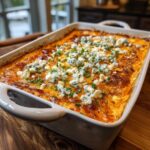A bubbling dish of hot Buffalo chicken dip topped with crumbled blue cheese and chives.